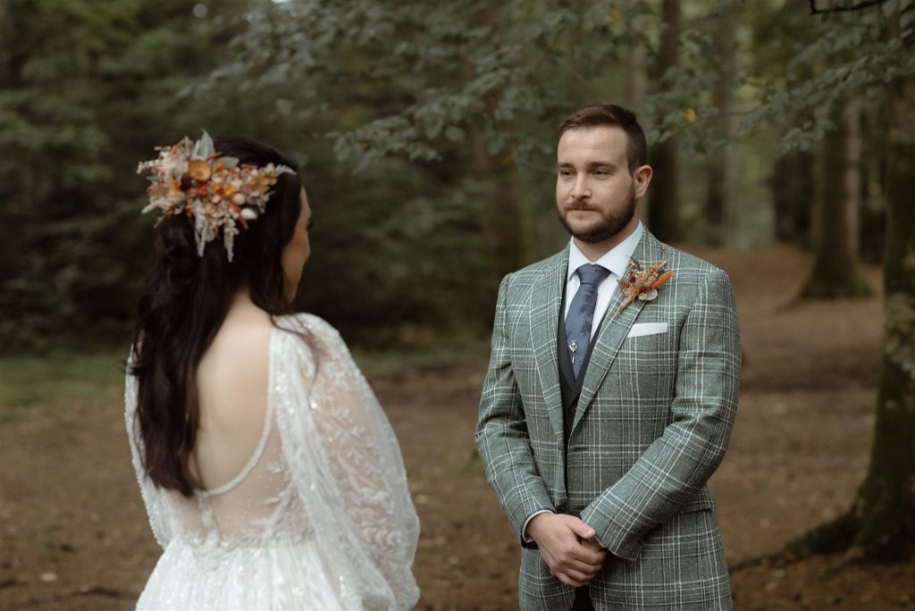 A bride and groom standing in the woodland during their wedding ceremony