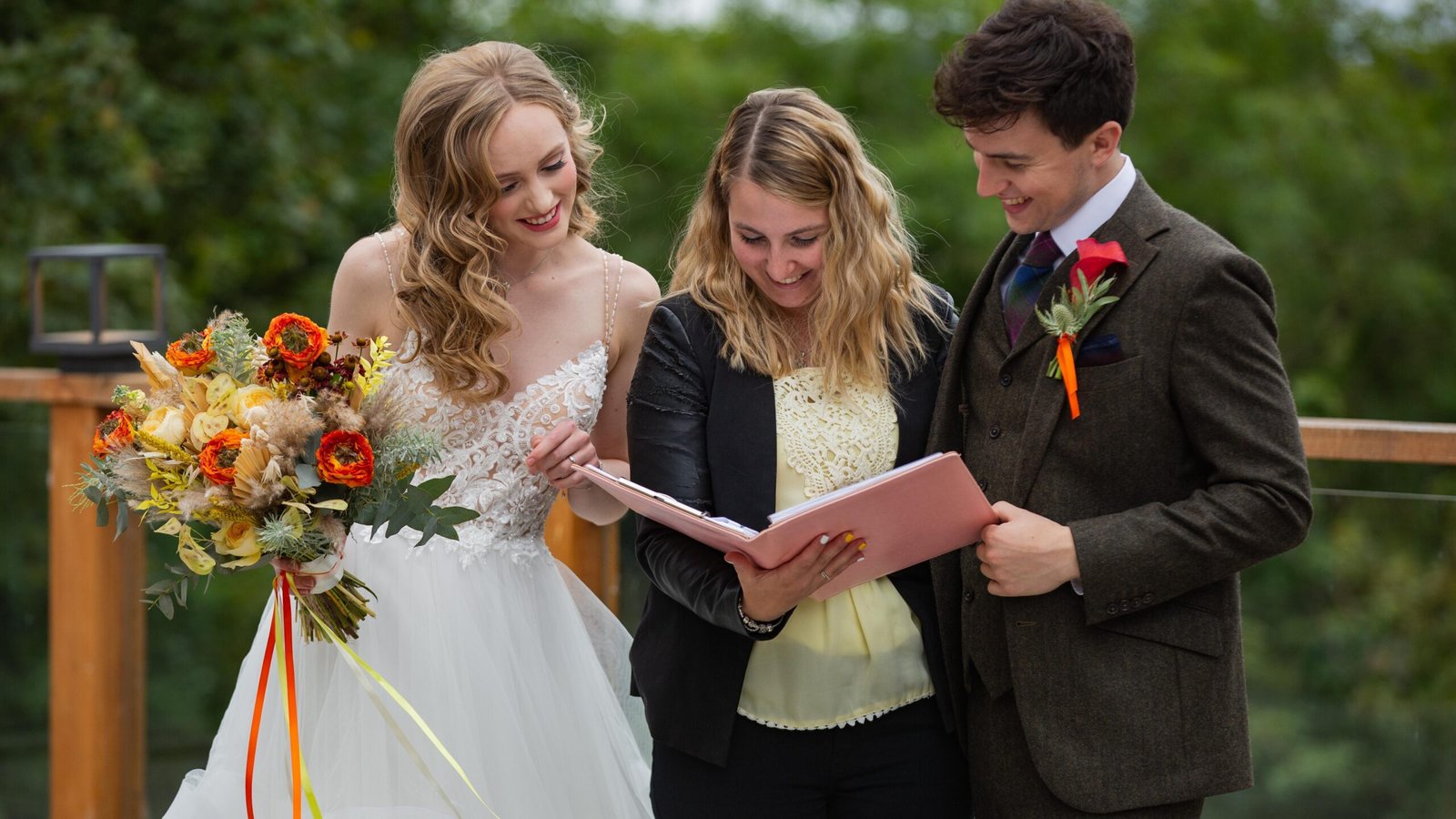 Wedding planner in Scotland holding a clipboard with the bride and the groom