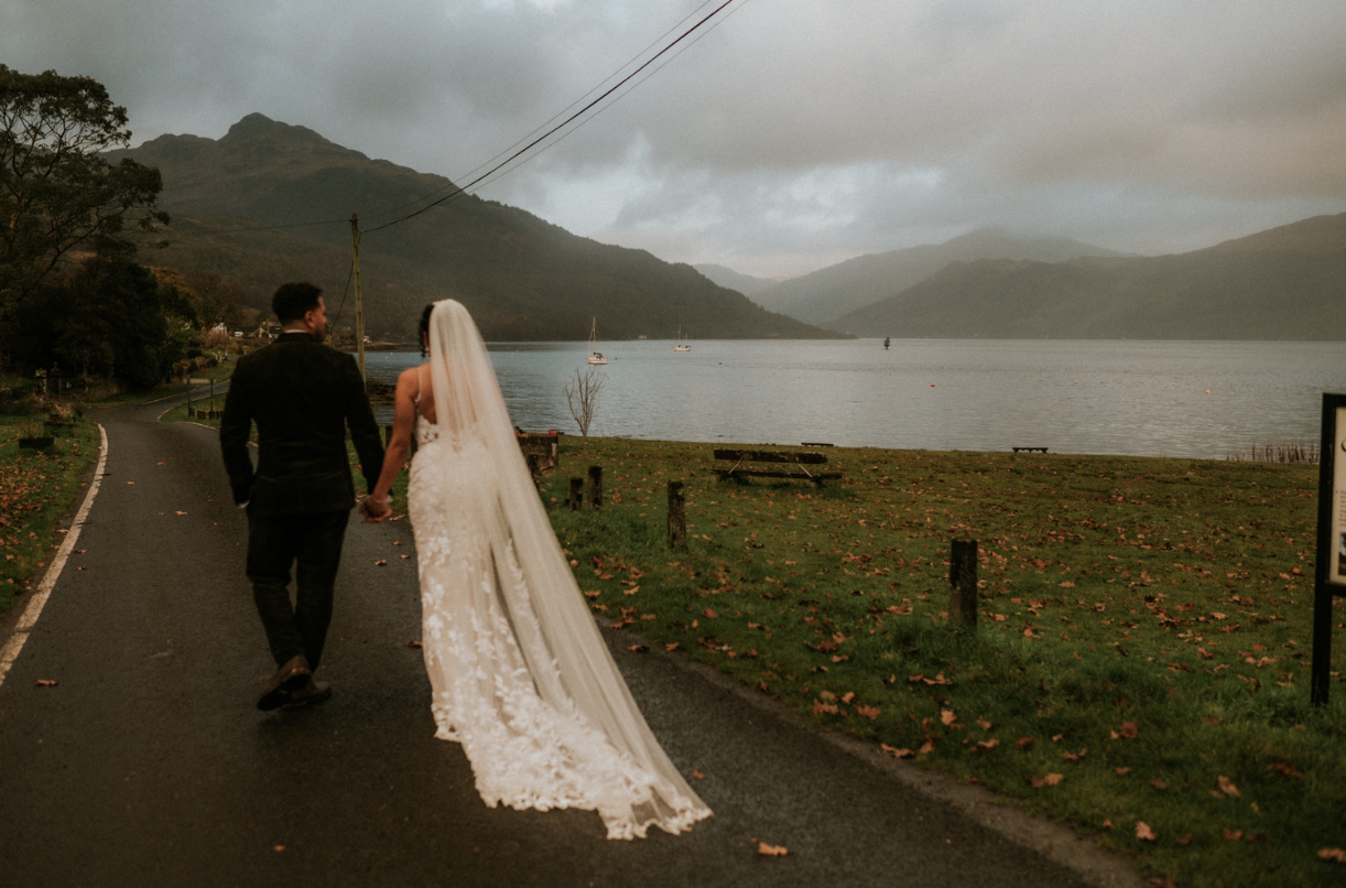 A bride and groom walking under a moody, cloudy Scottish Weather